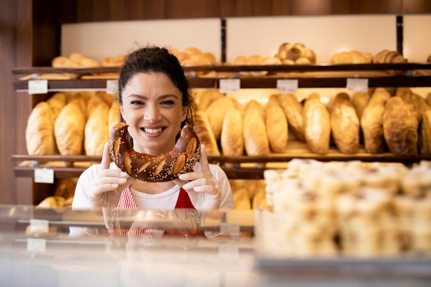 Vendedor de padaria segurando croissant crocante fresco para o cliente na padaria