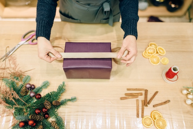 Vendedor decora caja de regalo con cinta dorada