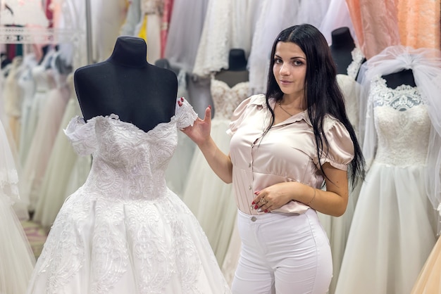 Foto vendedor em salão de casamento demonstrando vestidos para noiva