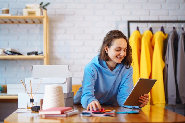 Vendedor empresario propietario de una pequeña empresa que usa una tableta para verificar los pedidos de la tienda de ropa de comercio electrónico