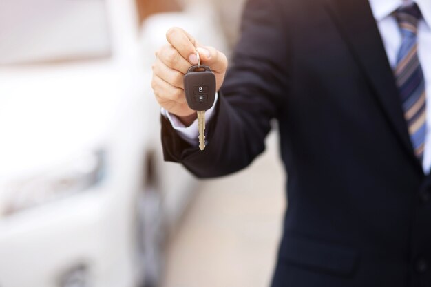 El vendedor entrega las llaves del auto nuevo al cliente en la sala de exhibición.