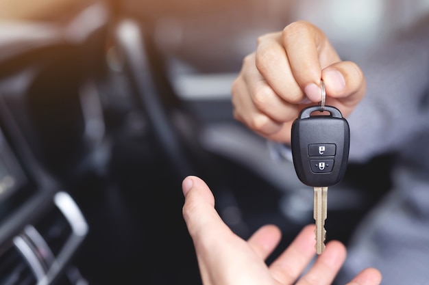 El vendedor entrega las llaves del auto nuevo al cliente en la sala de exhibición.