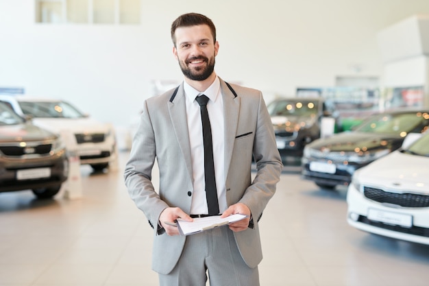 Vendedor feliz com contrato em pé no salão do automóvel