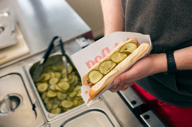 Vendedor haciendo hotdog en snack bar de comida rápida