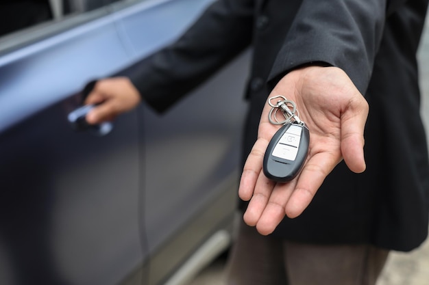 Foto vendedor irreconocible que ofrece la llave del auto vendiendo auto en la tienda del concesionario.