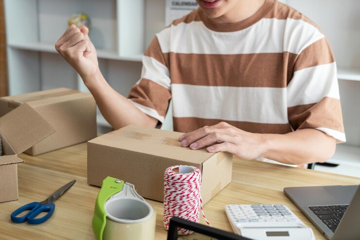 Foto el vendedor en línea que tiene una expresión facial alegre mientras coloca sus productos en la caja