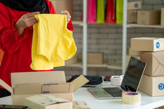 El vendedor en línea trabaja en la oficina en casa y empaca la caja de envío al cliente.