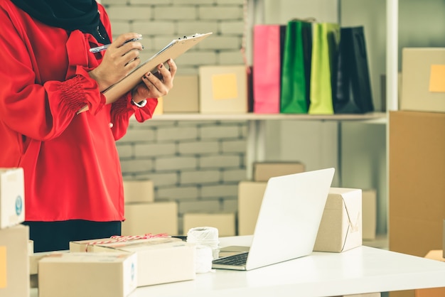 El vendedor en línea trabaja en la oficina en casa y empaqueta la caja de envío al cliente.