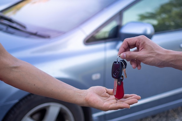 El vendedor masculino está enviando las llaves del auto a una clienta después de aceptar alquilar y comprar