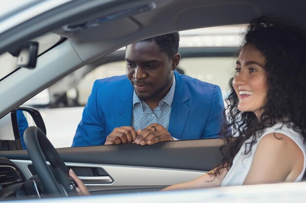 Vendedor negro describe las características del automóvil a una clienta