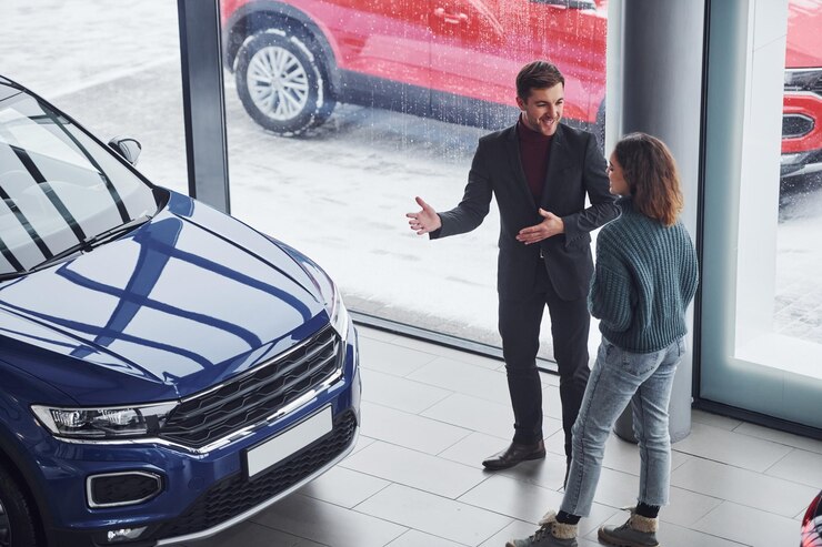 Foto vendedor profesional que ayuda a la joven a elegir un nuevo automóvil moderno en el interior.