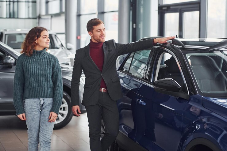 Foto vendedor profesional que ayuda a la joven a elegir un nuevo automóvil moderno en el interior.