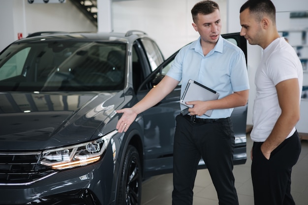 Vendedor que vende carros na concessionária homem escolhendo o carro no showroom