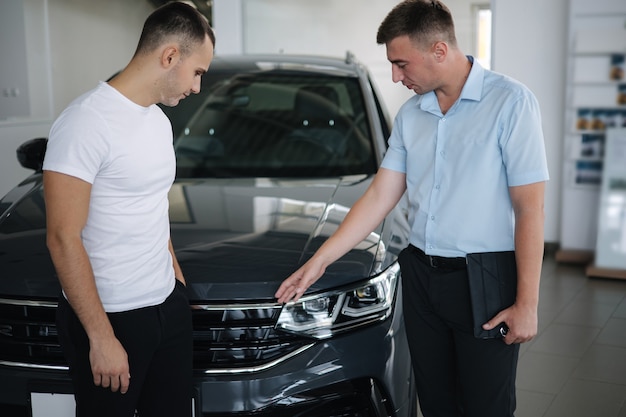 Vendedor que vende carros na concessionária homem escolhendo o carro no showroom