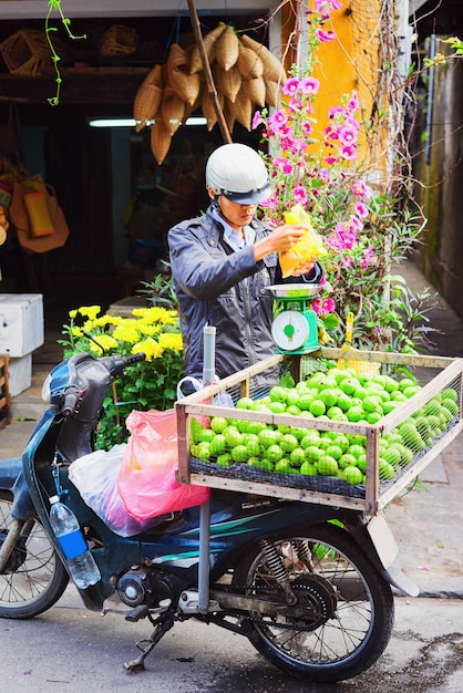 Vendedor que vende fruta de guayaba verde de la motocicleta en el mercado callejero en la ciudad vieja de Hoi An, Vietnam