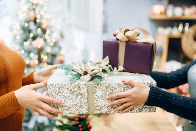 El vendedor del servicio de envoltura le da a la caja de regalo del cliente