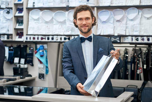 Foto vendedor sorrindo e preparando a compra para o cliente.