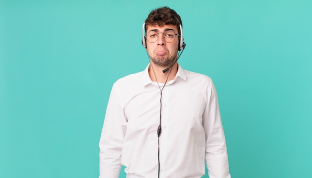 El vendedor telefónico se siente triste y quejumbroso con una mirada infeliz, llorando con una actitud negativa y frustrada