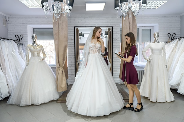 Vendedora ayudando a la joven novia en el salón de bodas