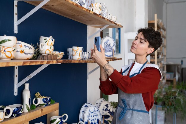 Una vendedora caucásica en una tienda de souvenirs toma fotografías de mercancías en el teléfono para publicarlas en las redes sociales