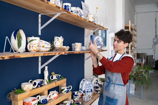 Una vendedora caucásica en una tienda de souvenirs toma fotografías de mercancías en el teléfono para publicarlas en las redes sociales