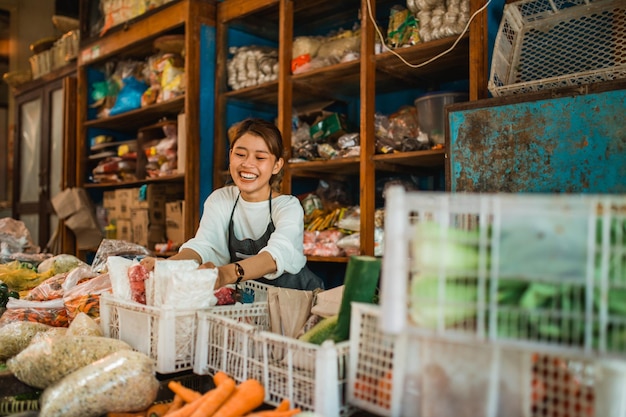 Foto vendedora de comestibles de color verde que pone los productos que vende en la cesta