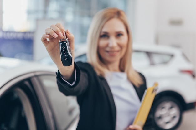 Vendedora de carro sorrindo alegremente segurando a chave do carro para a câmera