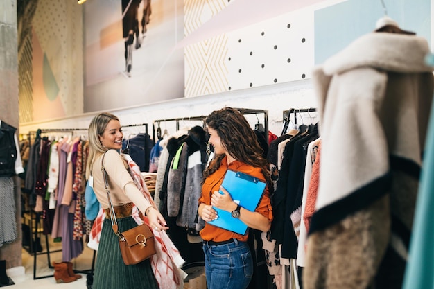 Vendedora feminina ajuda o comprador a escolher entre roupas diferentes.