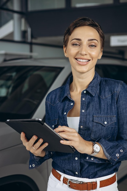 Vendedora no showroom de carros vendendo um carro