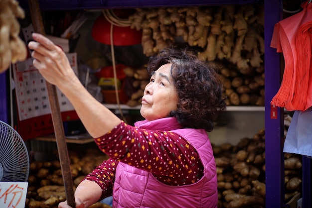 Foto vendedora que sostiene un palo mientras mira hacia el mercado