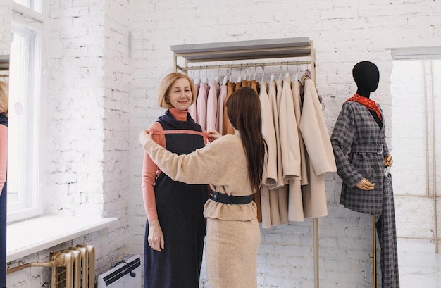 Una vendedora tomando medidas con un cliente anciano en una tienda de ropa