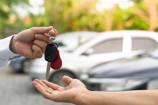 Vendendo conceito de acordo de venda de carro O revendedor dá as chaves do carro ao novo proprietário ou locatário com um contrato de seguro