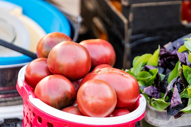 Vendendo tomates maduros e manjericão em um bazar de rua Legumes maduros frescos cultivados em uma fazenda em um pequeno balcão