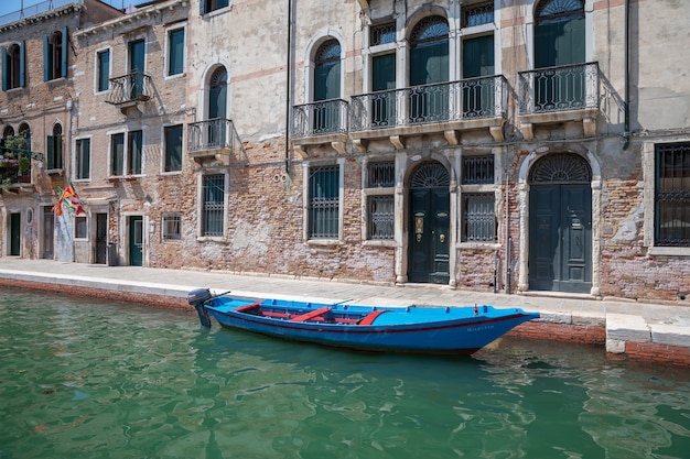 Venecia, Italia - 1 de julio de 2018: Vista panorámica del estrecho canal de Venecia con edificios históricos y barcos del puente. La gente se relaja y camina. Paisaje de día soleado de verano