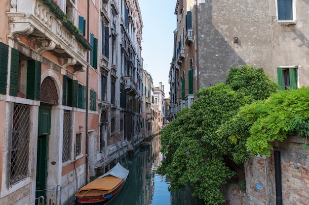 Venecia, Italia - 1 de julio de 2018: Vista panorámica del estrecho canal de Venecia con edificios históricos y barcos del puente. Paisaje de día soleado de verano