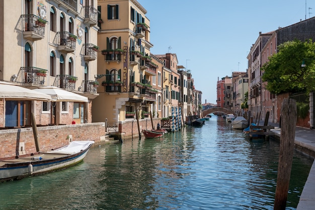 Venecia, Italia - 1 de julio de 2018: Vista panorámica del estrecho canal de Venecia con edificios históricos y barcos del puente. Paisaje de día soleado de verano