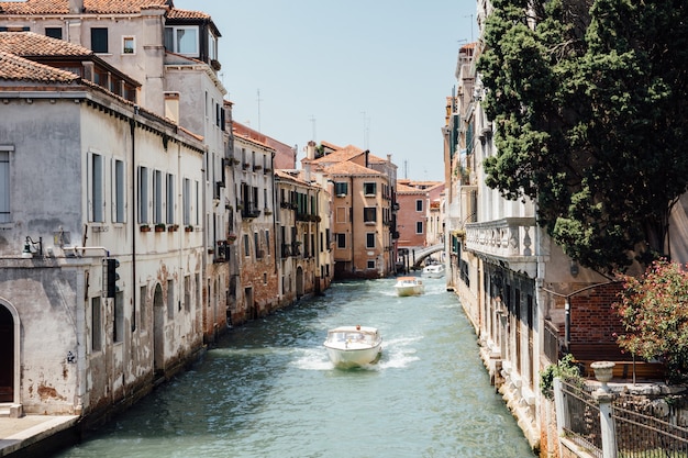 Venecia, Italia - 1 de julio de 2018: Vista panorámica del estrecho canal de Venecia con edificios históricos y tráfico de barcos desde el puente Foscari. Paisaje de día soleado de verano y cielo azul