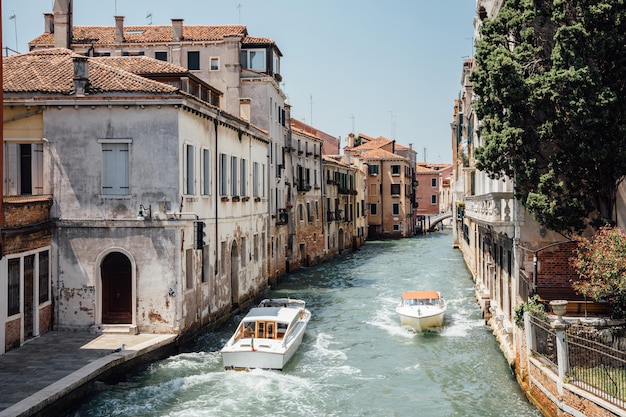 Venecia, Italia - 1 de julio de 2018: Vista panorámica del estrecho canal de Venecia con edificios históricos y tráfico de barcos desde el puente Foscari. Paisaje de día soleado de verano y cielo azul.