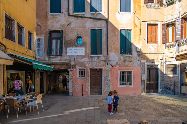 VENECIA ITALIA 27 de agosto de 2021 madres mirando el escaparate mientras las hijas pequeñas juegan en la plaza de las calles de Venecia