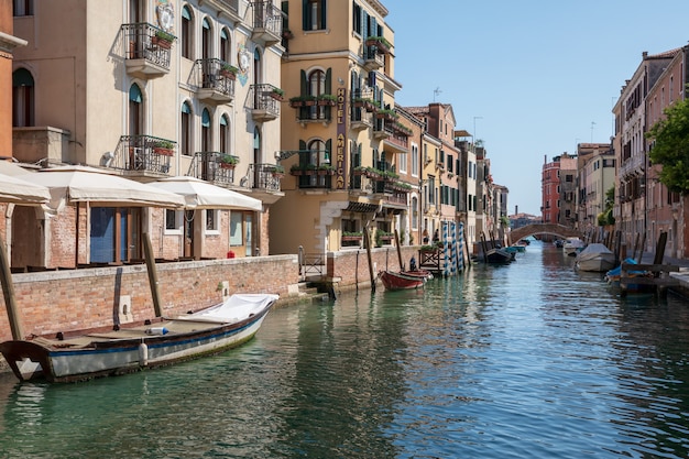 Venedig, Italien - 1. Juli 2018: Panoramablick auf den schmalen Kanal von Venedig mit historischen Gebäuden und Booten von der Brücke. Landschaft des sonnigen Sommertages