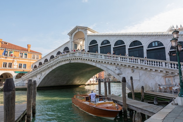 Veneza, Itália - 1 de julho de 2018: Vista panorâmica da Ponte Rialto (Ponte di Rialto) é a mais antiga das quatro pontes que medem o Grande Canal de Veneza. Paisagem de dia ensolarado de verão e céu azul