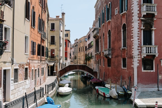 Veneza, Itália - 1 de julho de 2018: Vista panorâmica do canal estreito de Veneza com edifícios históricos e barcos da ponte. Paisagem de dia ensolarado de verão