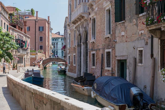 Veneza, itália - 1 de julho de 2018: vista panorâmica do canal estreito de veneza com edifícios históricos e barcos da ponte. paisagem de dia ensolarado de verão