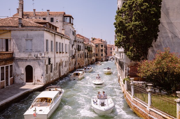 Veneza, Itália - 1 de julho de 2018: Vista panorâmica do estreito canal de Veneza com tráfego de edifícios e barcos históricos da ponte Foscari. Paisagem de dia ensolarado de verão e céu azul