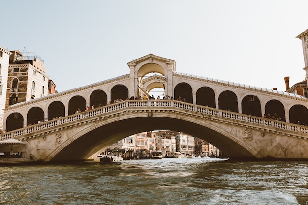 Veneza, itália - 2 de julho de 2018: vista panorâmica da ponte de rialto (ponte di rialto) é a mais antiga das quatro pontes que medem o grande canal de veneza da gôndola. dia ensolarado de verão e céu azul