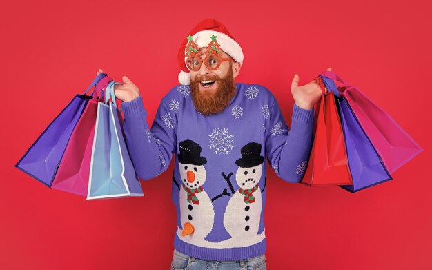 Foto venta de compras de año nuevo sorprendió al hombre con la bolsa de compras después de la venta de año nuevo el hombre de santa con la mochila de compra de año nuevo en venta aislado en rojo