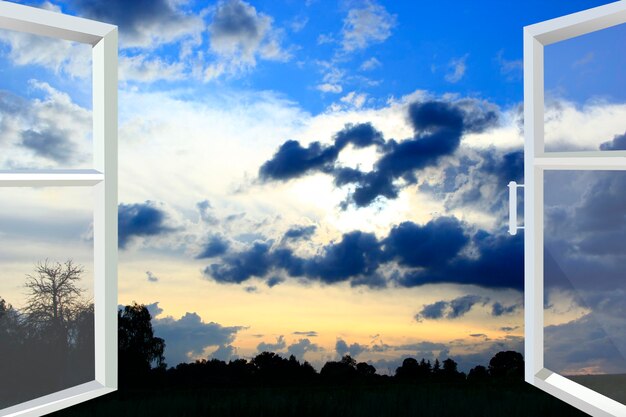 Foto ventana abierta al atardecer con nubes oscuras frescura nocturna ventana blanca abierta con vista a nubes oscuras