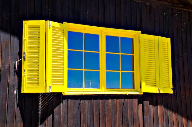 Ventana amarilla en la pared de madera, Algarve, Portugal.