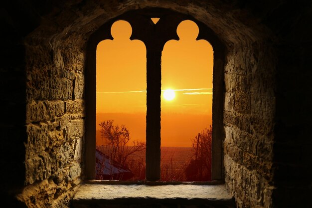 Foto ventana de arco de un edificio antiguo contra el cielo durante la puesta de sol