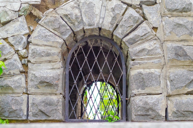 Una ventana arqueada con una celosía en una vieja pared de ladrillos.